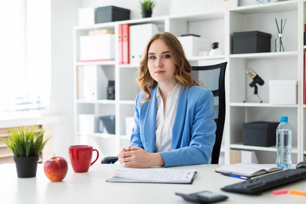 Beautiful young girl is sitting at the table in the office.