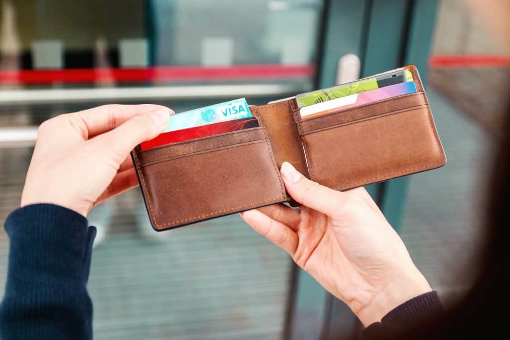 A women taking a visa card from a brown wallet