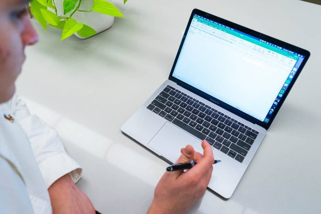 A person looking at laptop holding a pen